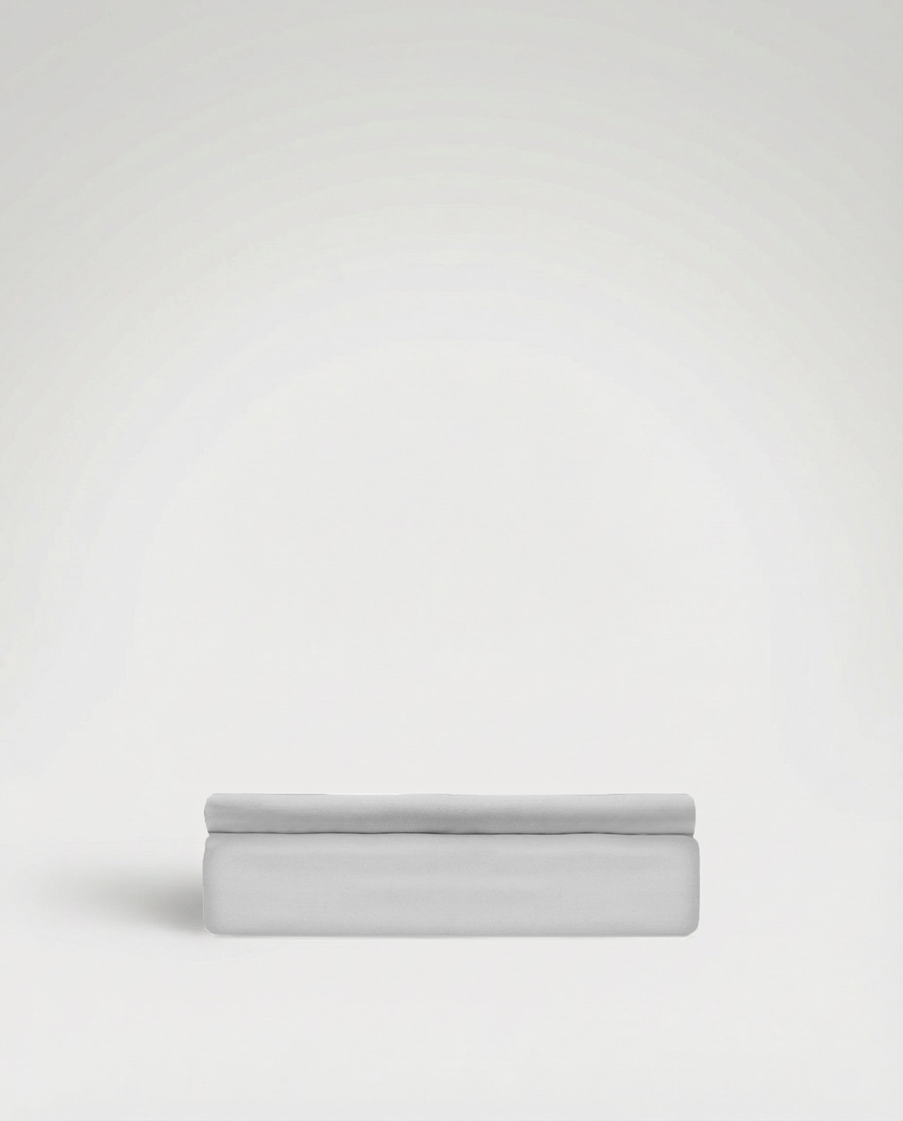 Neatly folded flat sheet in smooth, soft light grey Tencel sateen fabric against plain background.