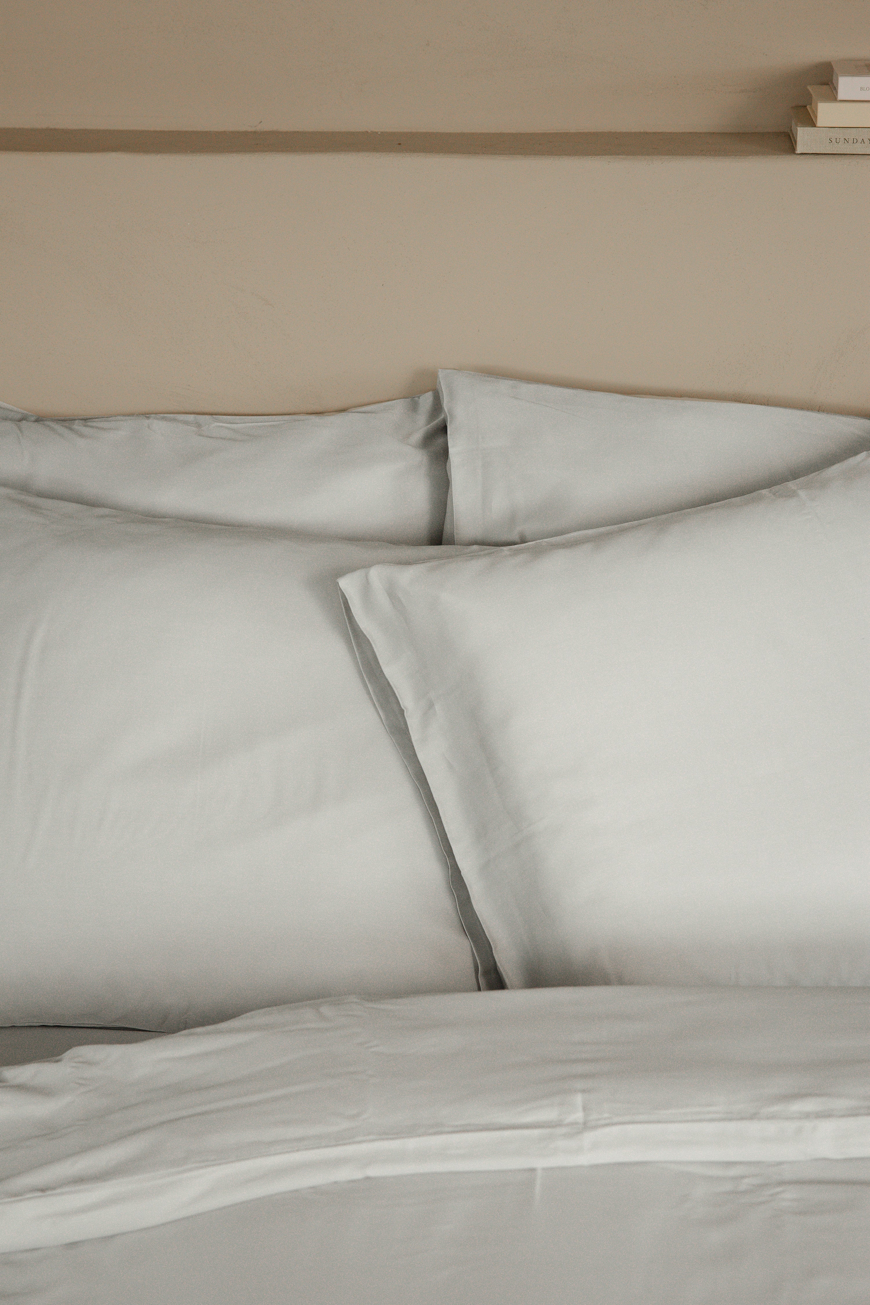 Set of soft, light grey Tencel™ sateen pillowcases on matching bedding with smooth finish.