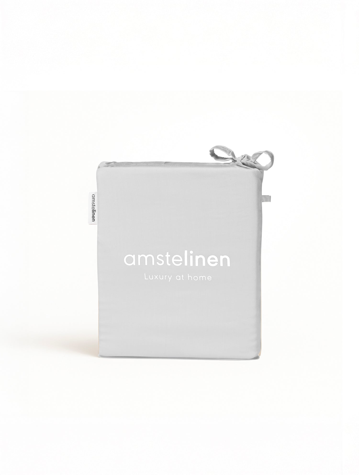 Folded white fitted sheet in minimalist packaging with Amstelinen logo and drawstring closure.