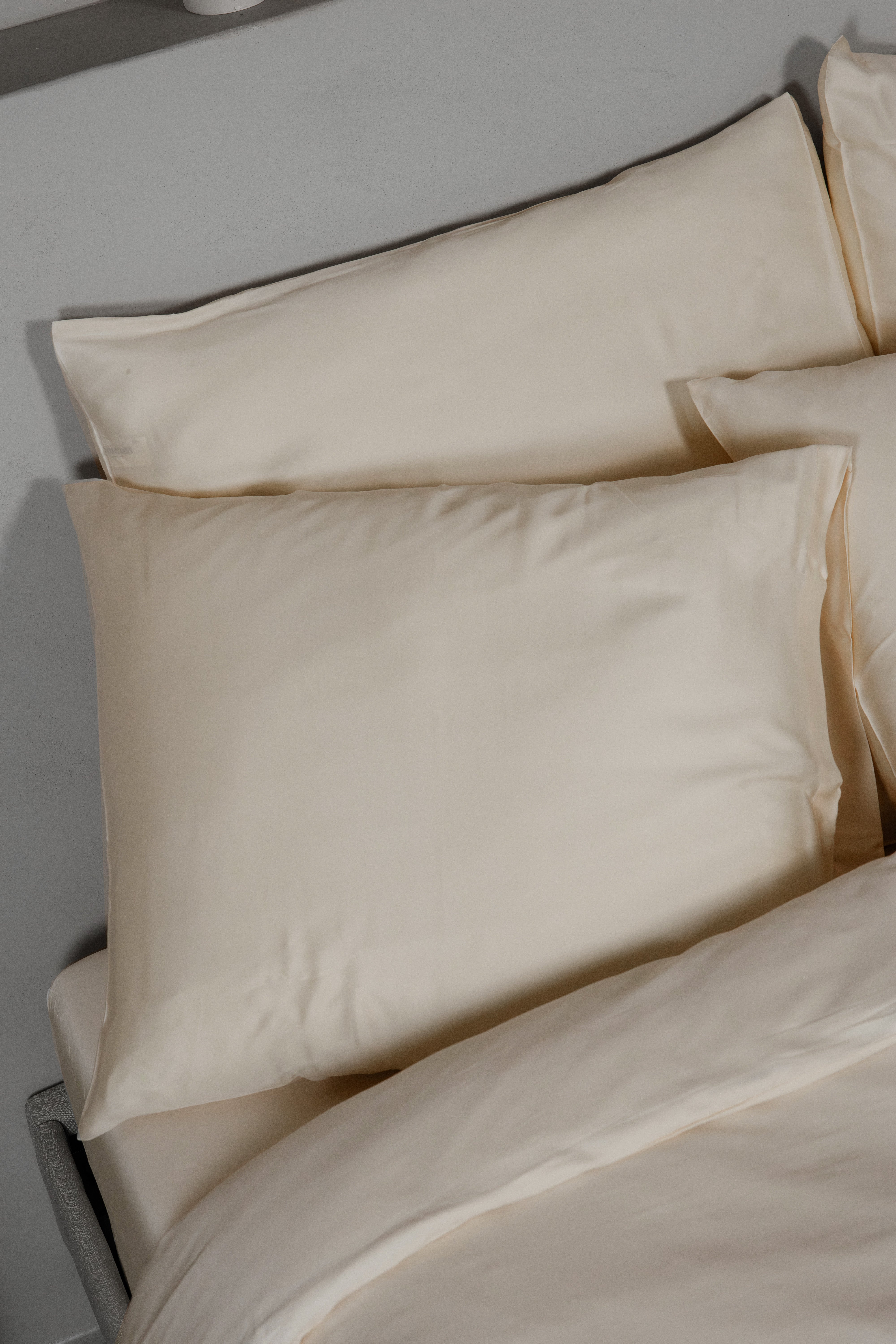 Classic ivory Tencel™ sateen pillowcases on a bed with matching bedding, smooth and soft texture.