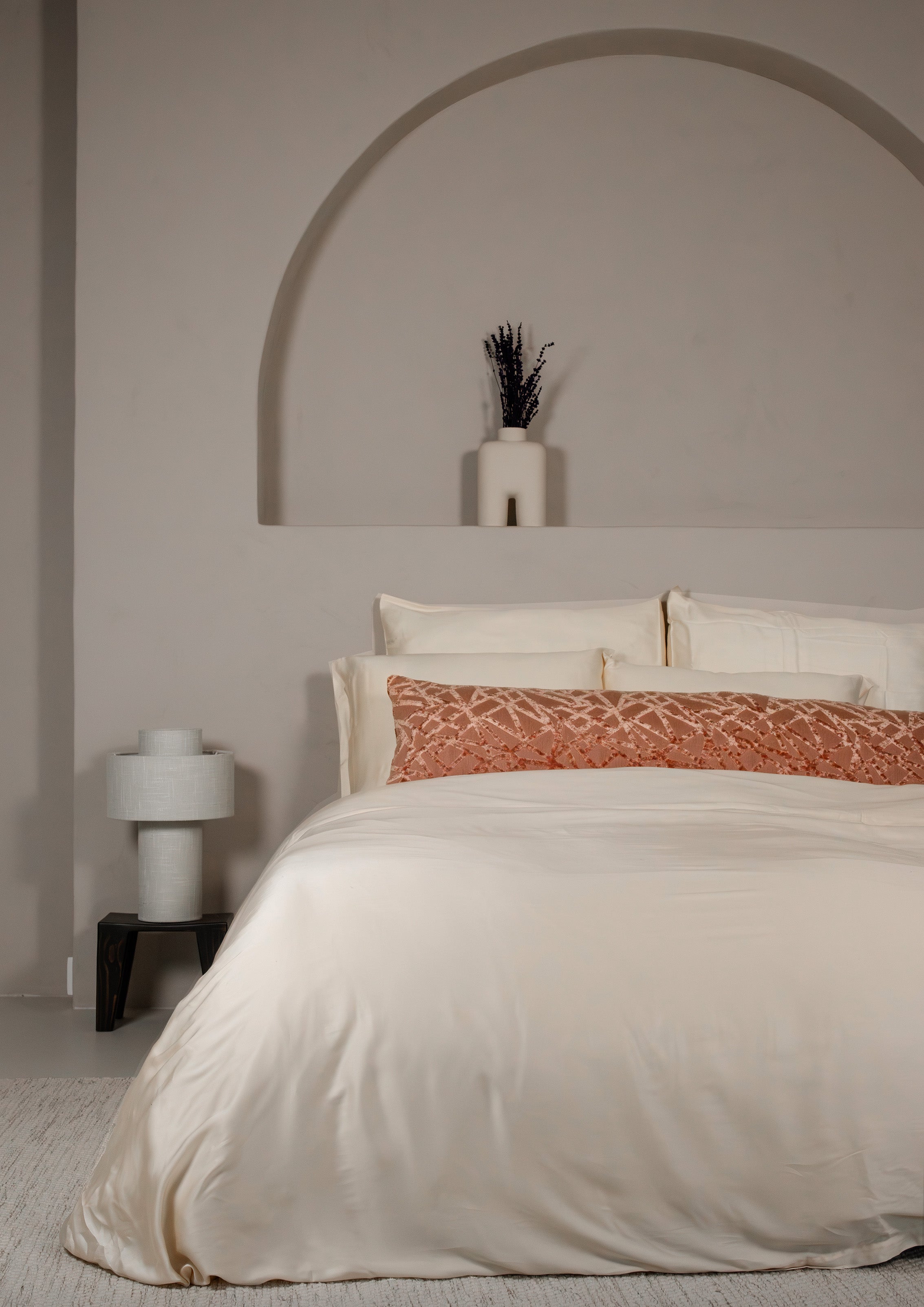 Classic ivory Tencel™ sateen flat sheet on bed with matching pillowcases and rust-colored accent pillow.