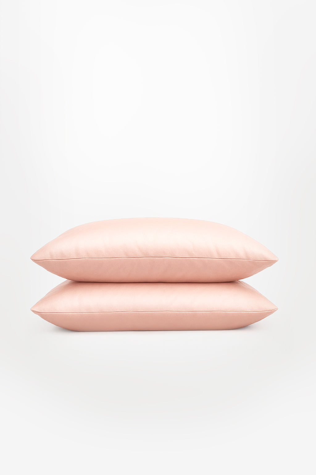 Stack of two soft blush pink Tencel™ sateen pillowcases on white background.