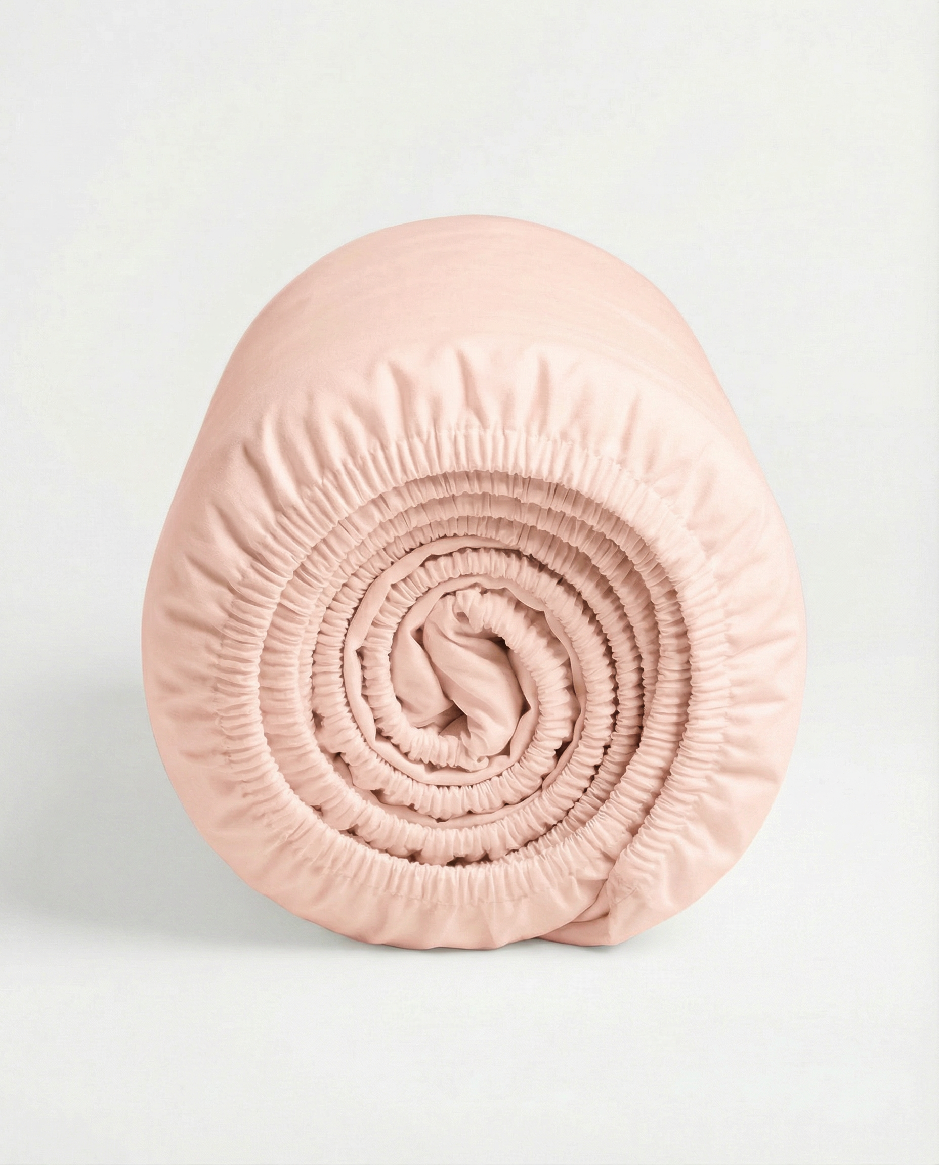 Rolled Whisper Rose Tencel™ sateen fitted sheet with elastic edges on white background.
