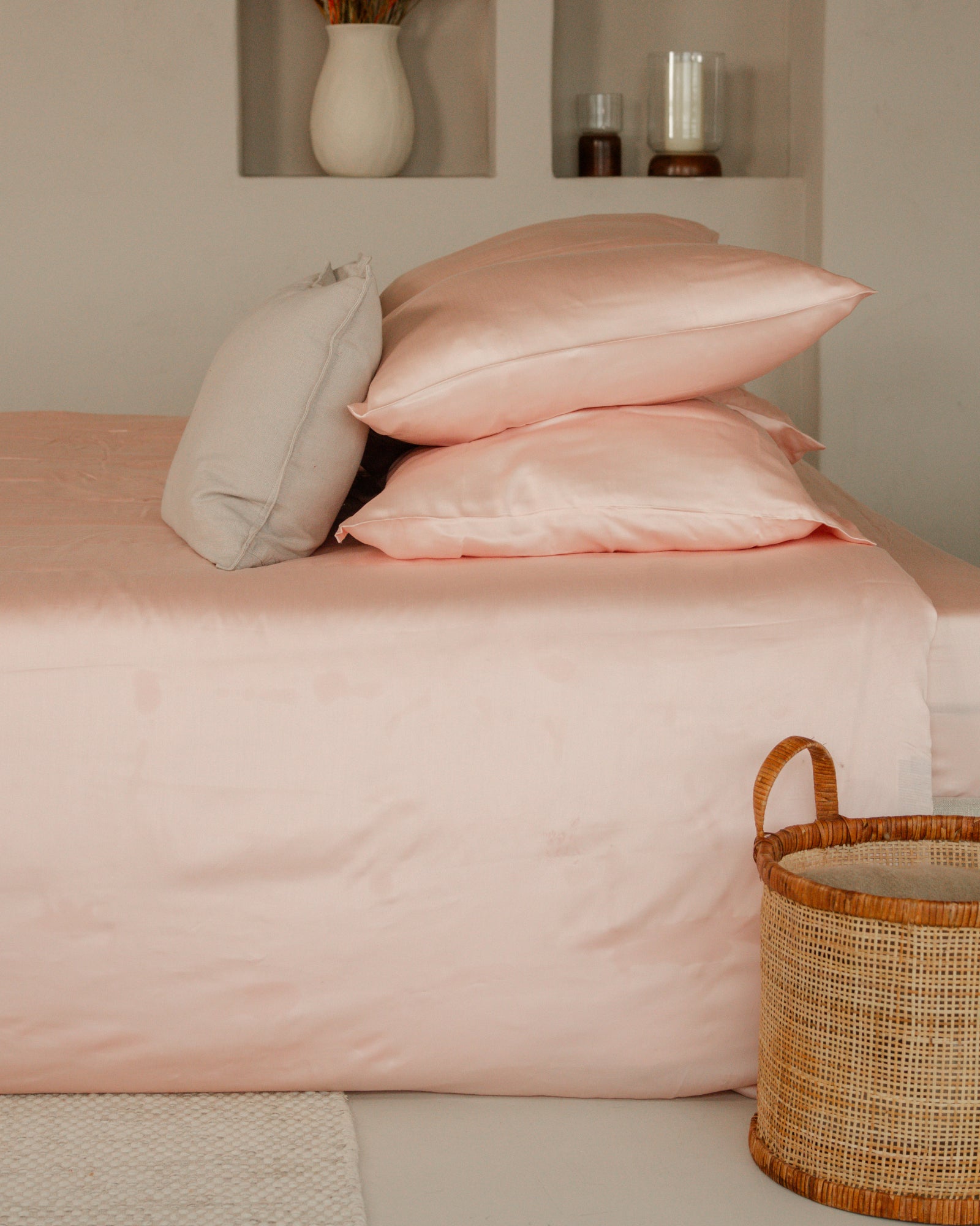 Soft blush pink Tencel sateen duvet cover set with matching pillowcases on bed, styled with neutral decor and wicker basket.
